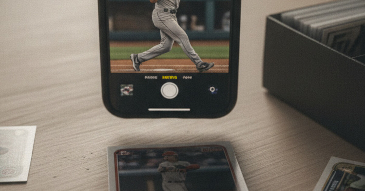 A phone scanning a sports card on a desk with several other cards spread around it