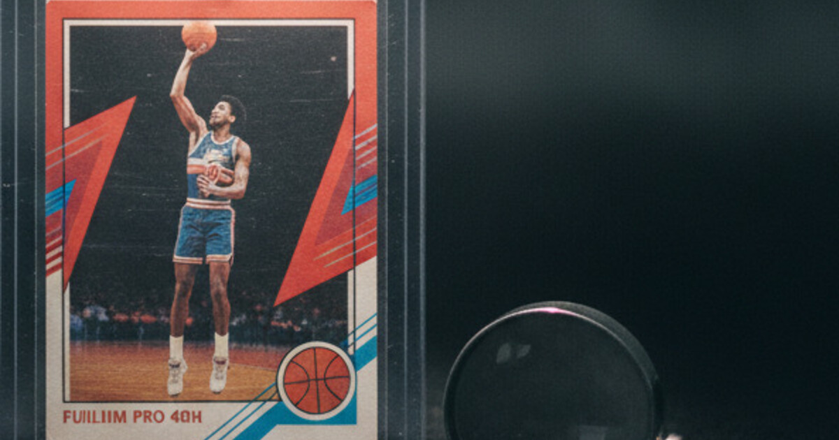 Vintage 1980s basketball card with red and blue border in a rigid holder next to a magnifying loupe