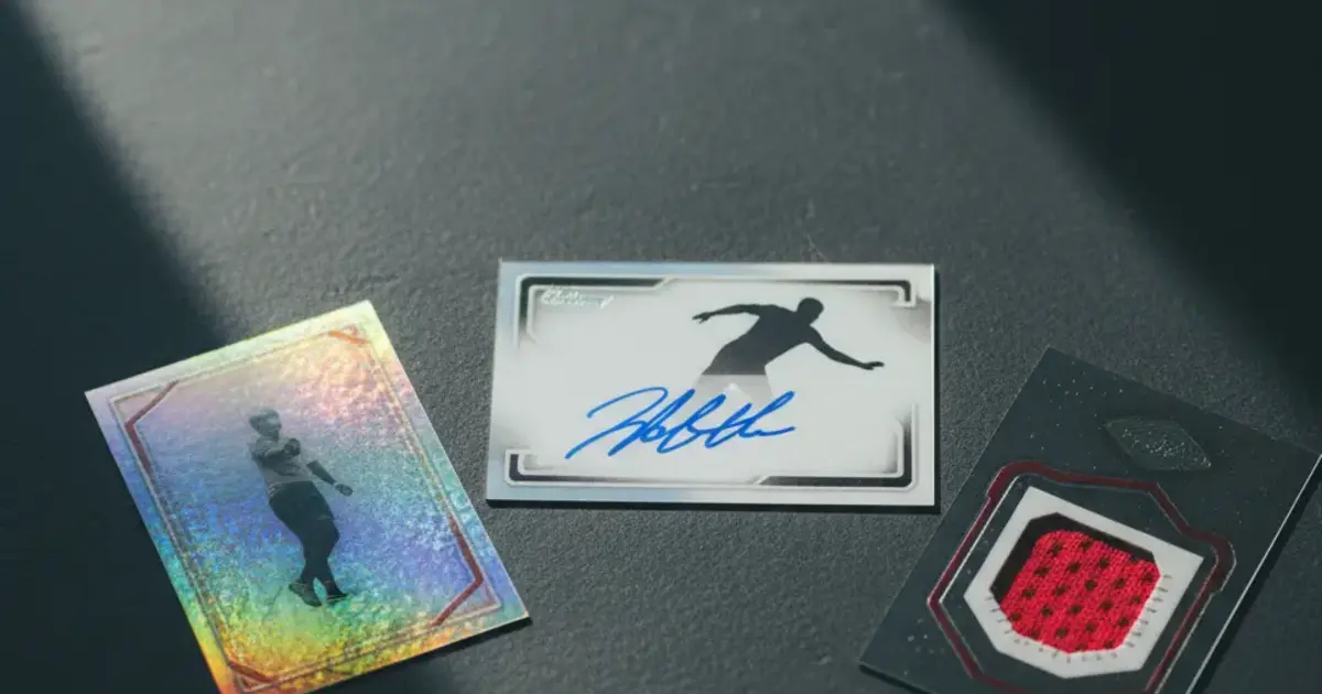 Three sports card inserts displayed on a dark collector's mat showing different designs: holographic foil, an autograph, and a jersey swatch window